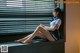 A woman sitting on a window sill with her legs crossed.