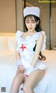 A woman dressed as a nurse sitting on a bed.