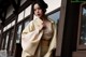 A woman in a yellow kimono leaning against a window.