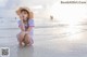 A woman in a straw hat sitting on the beach.