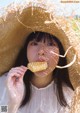 A woman in a straw hat eating a piece of food.