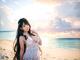 A woman in a white dress standing on a beach.