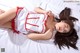 A woman laying on top of a bed in a white and red dress.