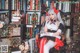 A woman sitting on a chair in front of a bookshelf.