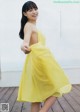 A woman in a yellow dress posing for a picture.