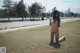 A naked woman kneeling on the grass in a park.