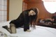 A woman in a black dress is sitting on a bed.